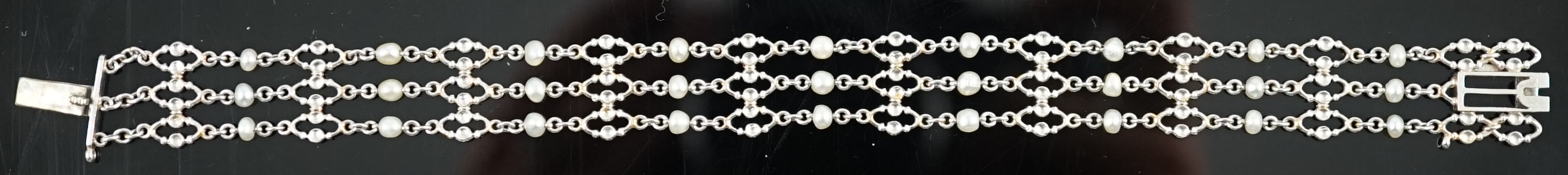 An early to mid 20th century white gold and seed pearl set three row chain link bracelet